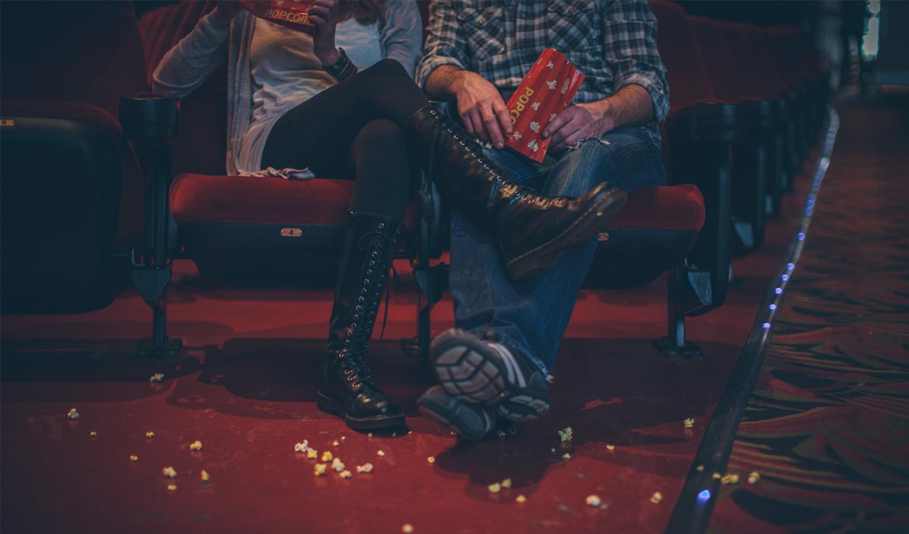 first date ideas: Couple with popcorn on the floor at movie theater